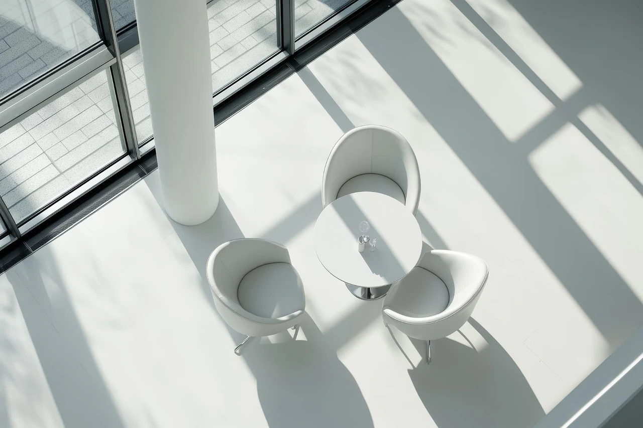 White chairs around a small table in a sunlit lobby, seen from above