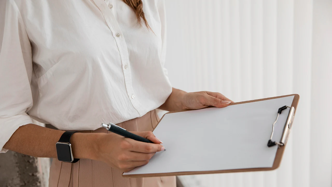 A consultant in a white shirt taking notes on a clipboard