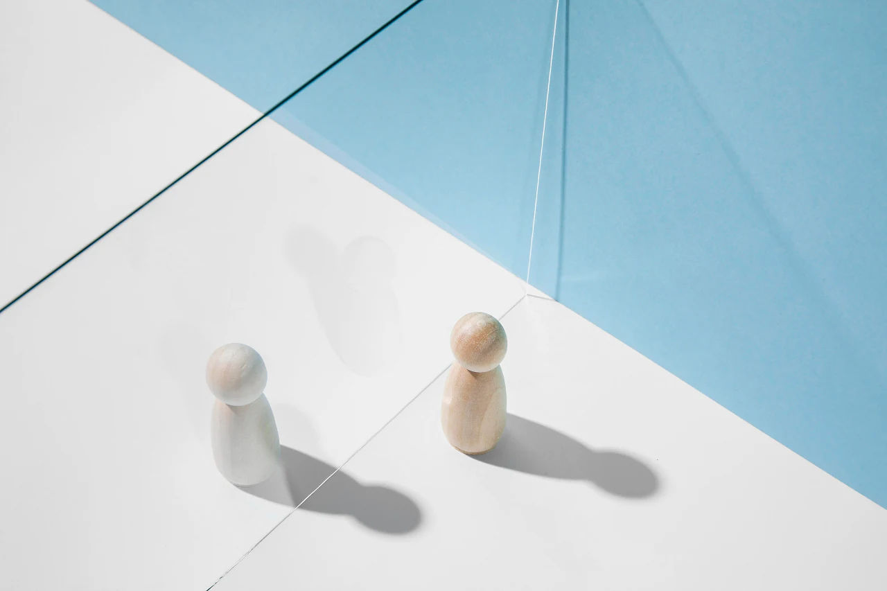 Two wooden figures facing each other on a white and pale blue surface