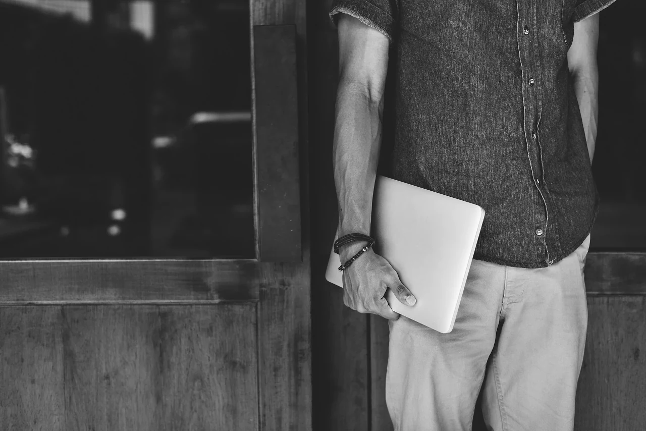 A man in a shirt holding a laptop, in black and white