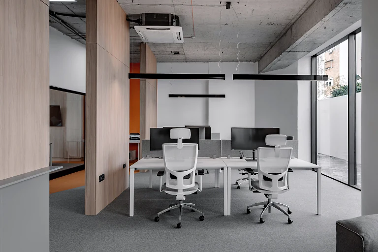 A finished open-plan office with desks, white chairs and timber walls