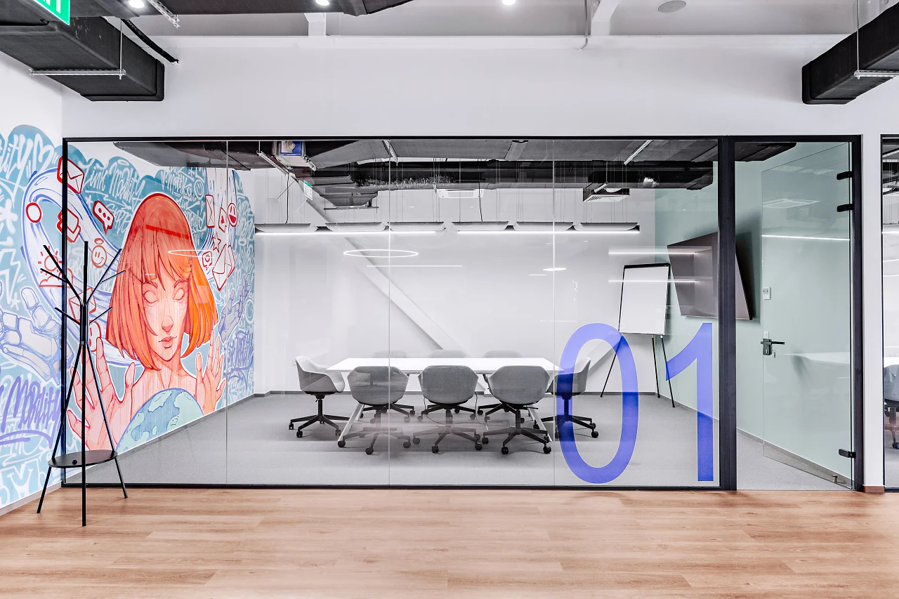 A glass meeting room behind the mural, a blue 01 on the glass