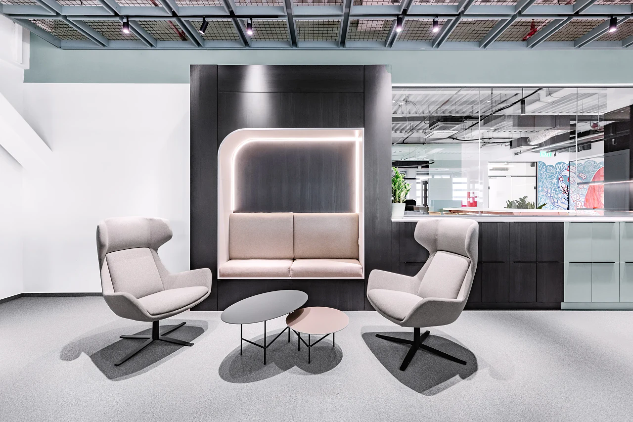 A lit booth and two lounge chairs around low tables