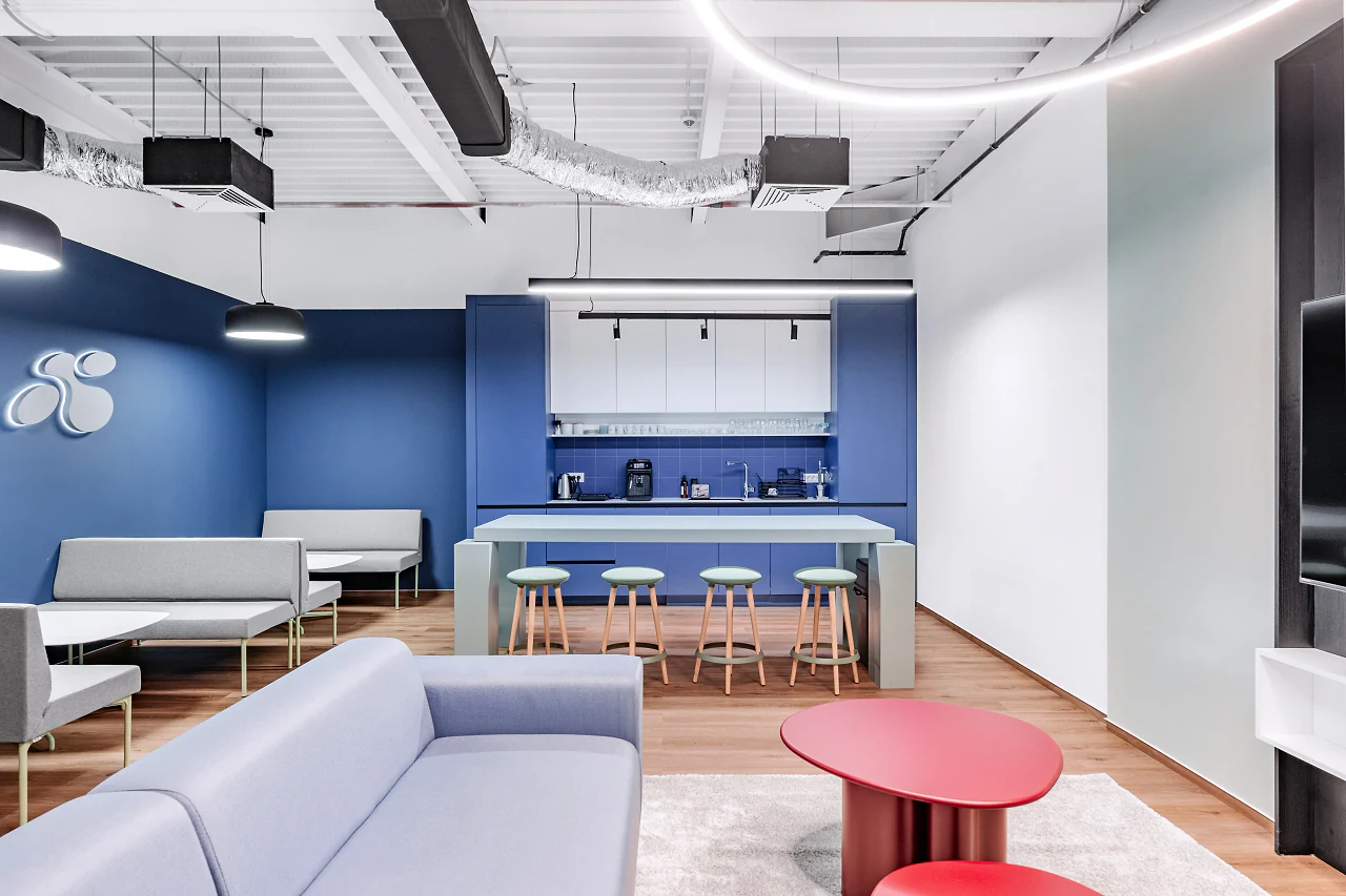 A breakout kitchen with a blue wall, bar stools and a sofa