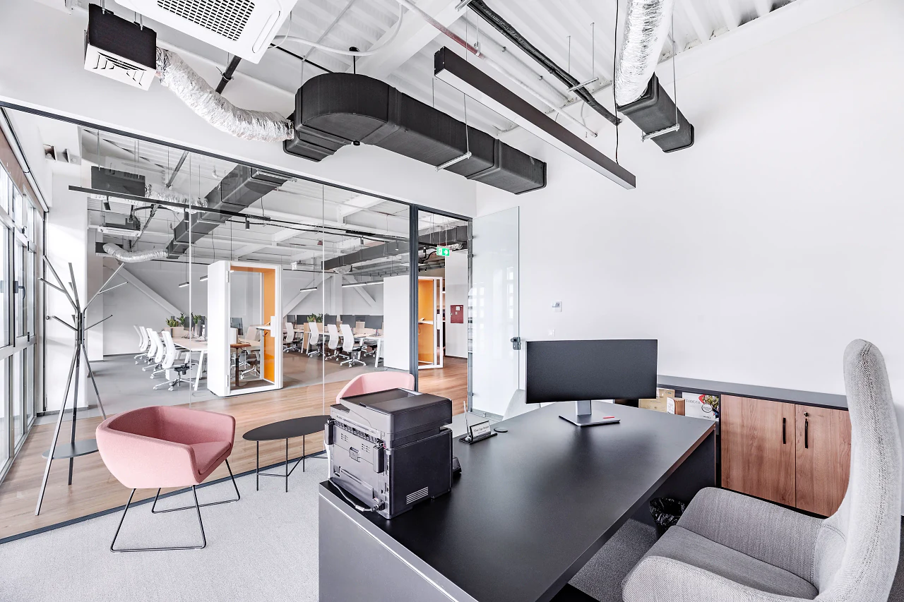 A desk with a monitor and a pink lounge chair