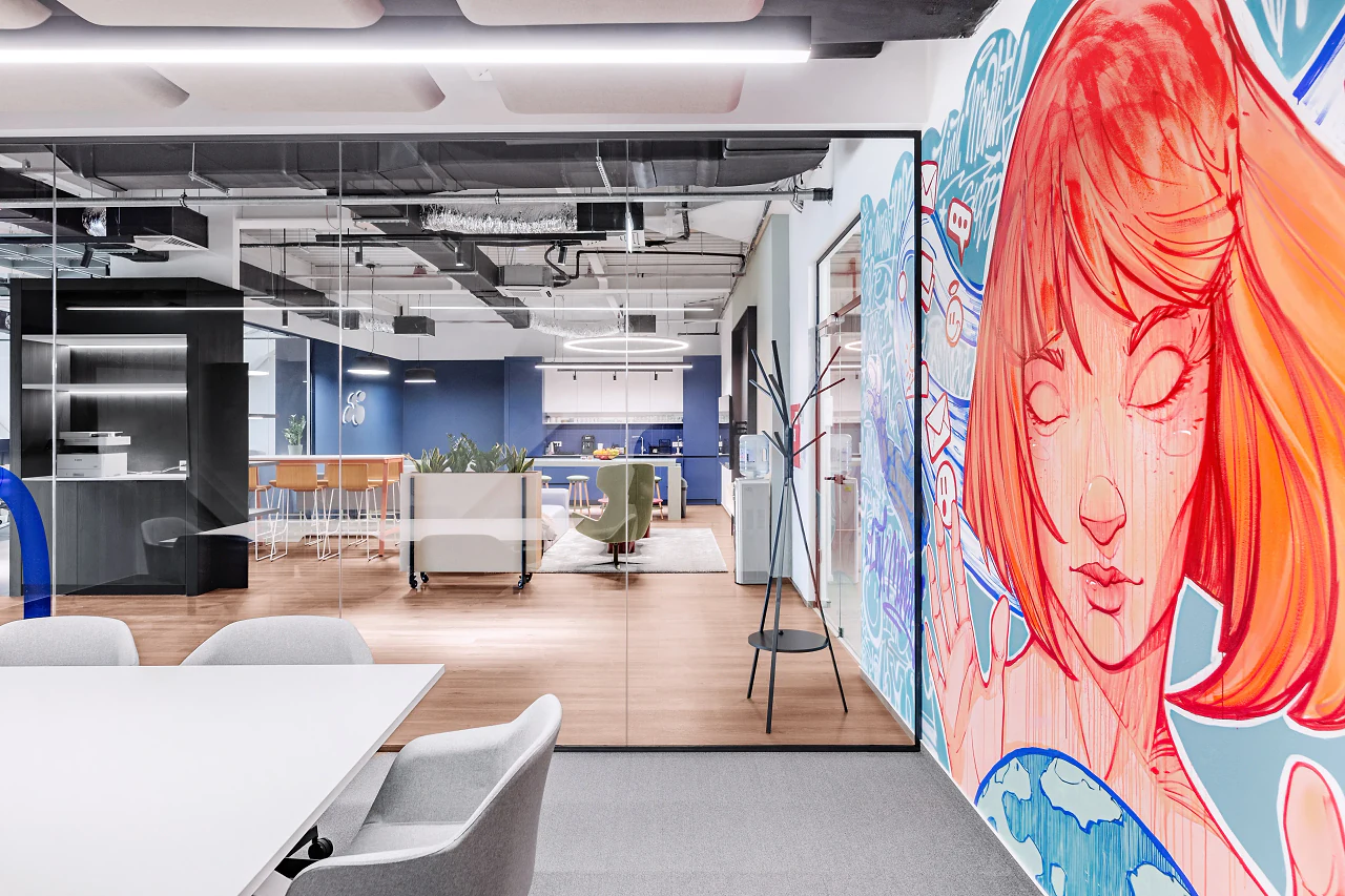 The mural running along a corridor beside an open work area