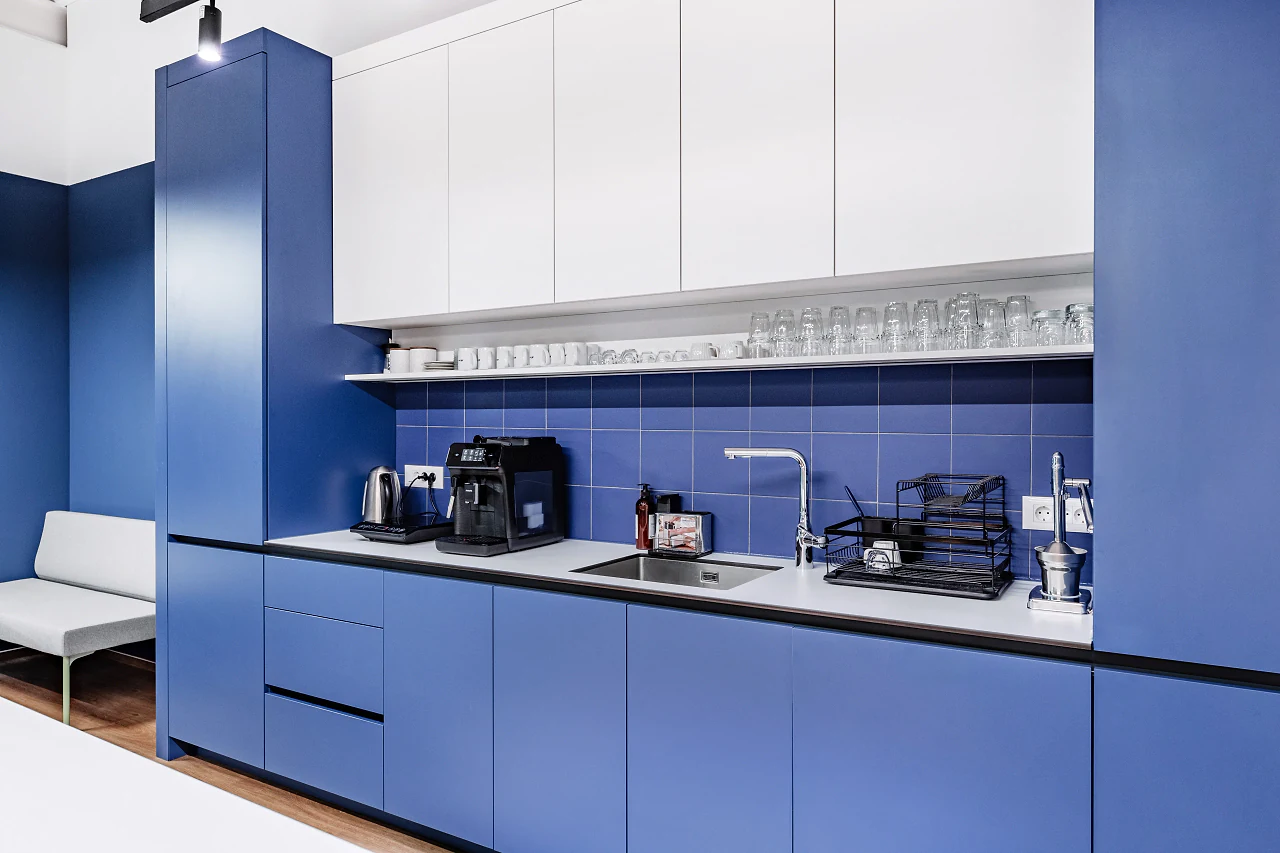 A blue kitchen with white upper cupboards