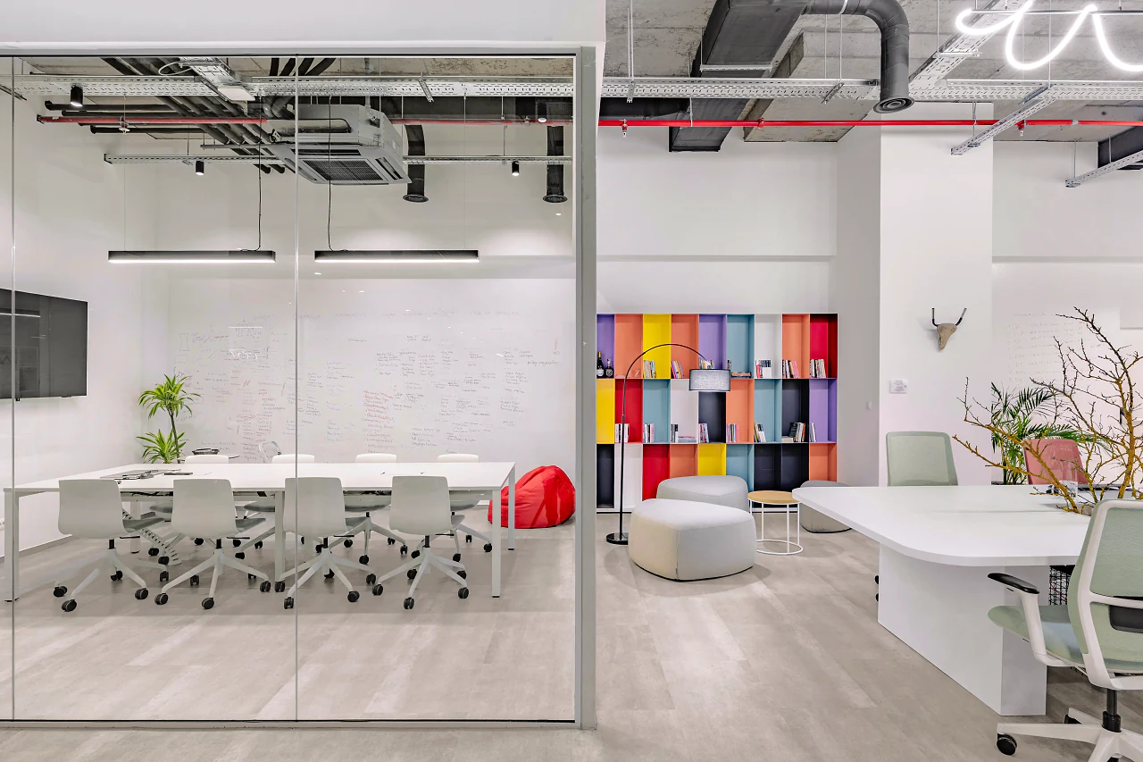 A glass meeting room with a long table beside a wall of colourful lockers
