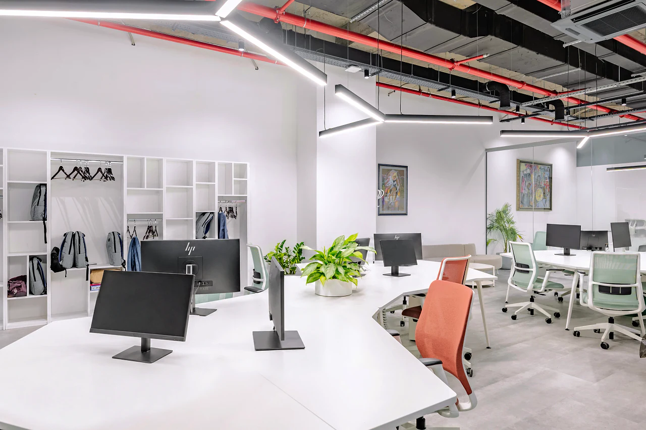 A curved white desk corner with an orange chair and shelving