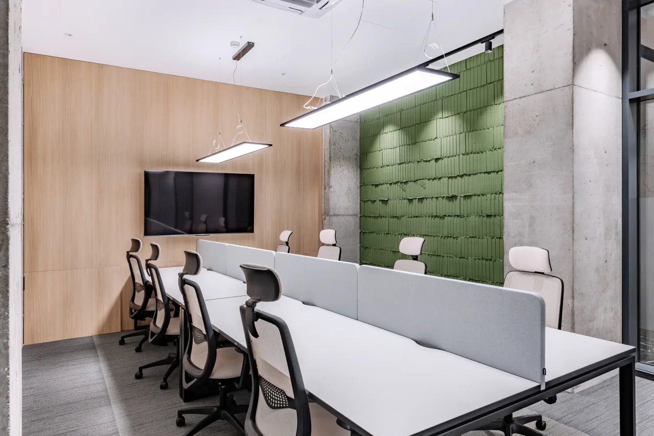 Desks facing a screen in front of a green acoustic wall