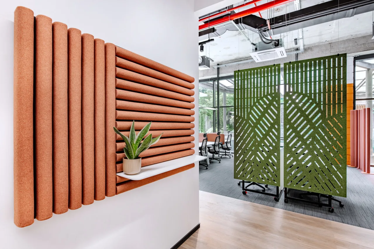 An orange ribbed wall panel with a plant, a green slatted screen beyond
