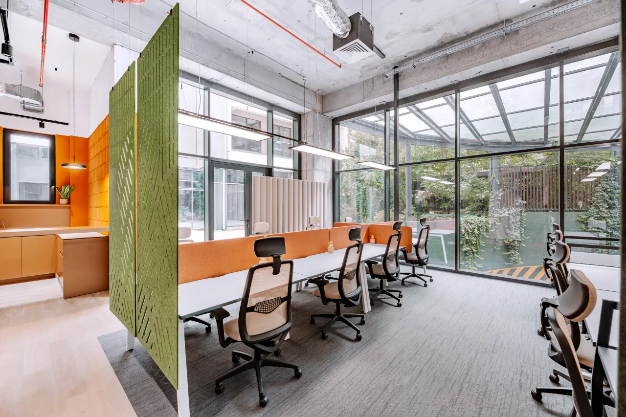 Desks along a glazed wall, a green screen between them