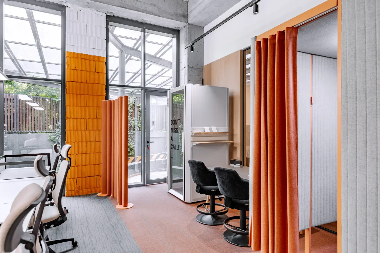 An orange brick wall beside a curtained phone booth