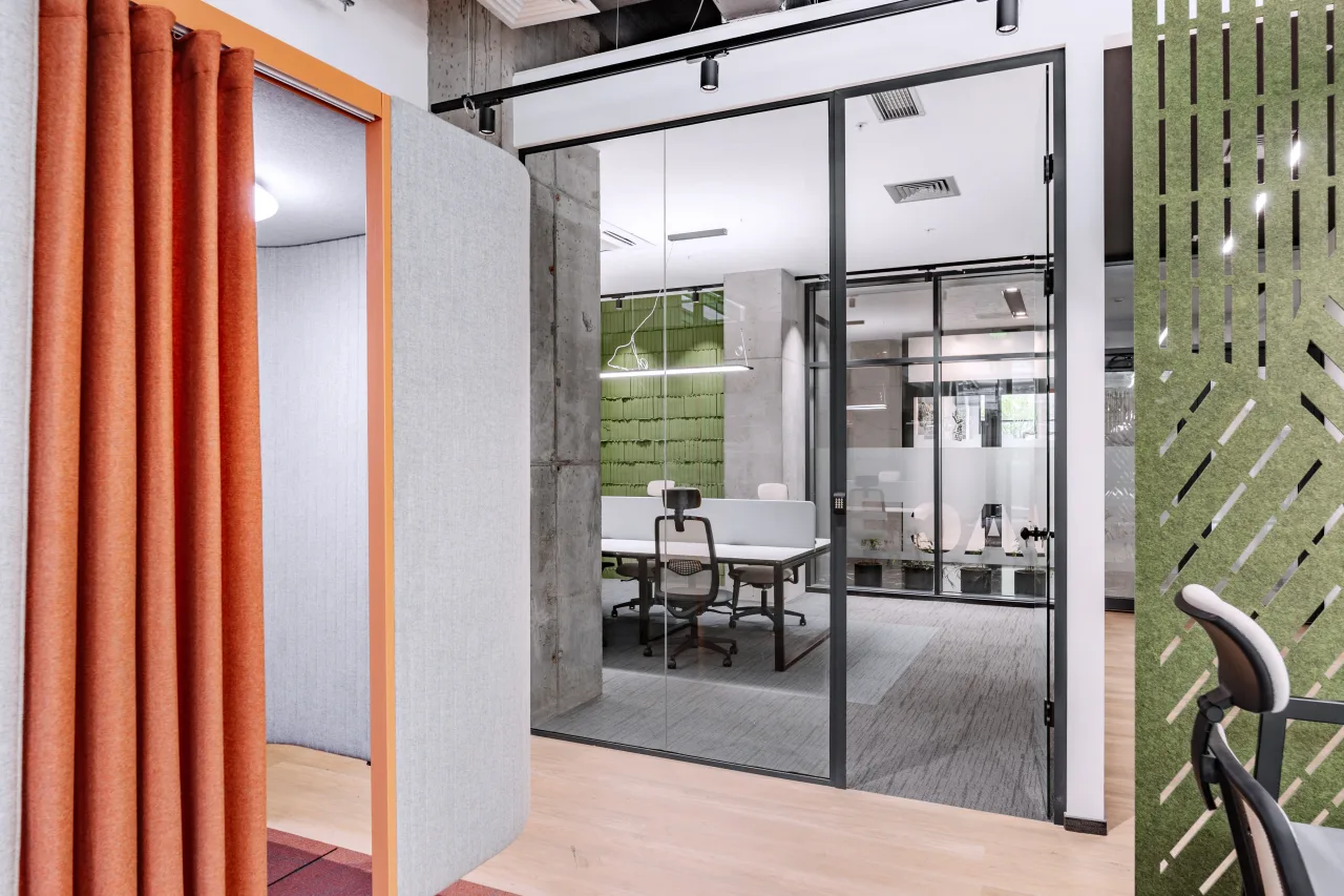 An orange curtain booth beside a glass meeting room