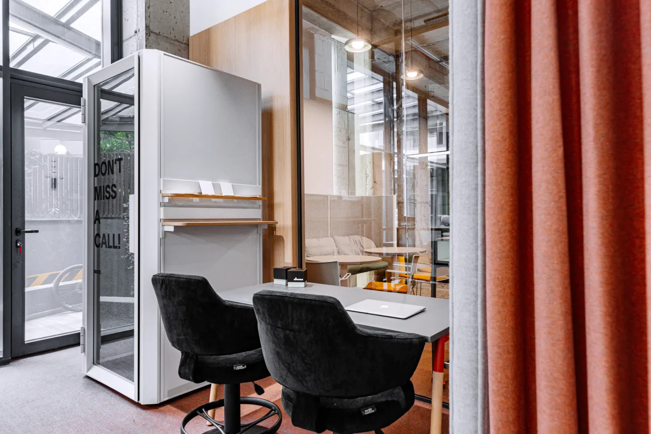 Phone booths with orange curtains and black chairs