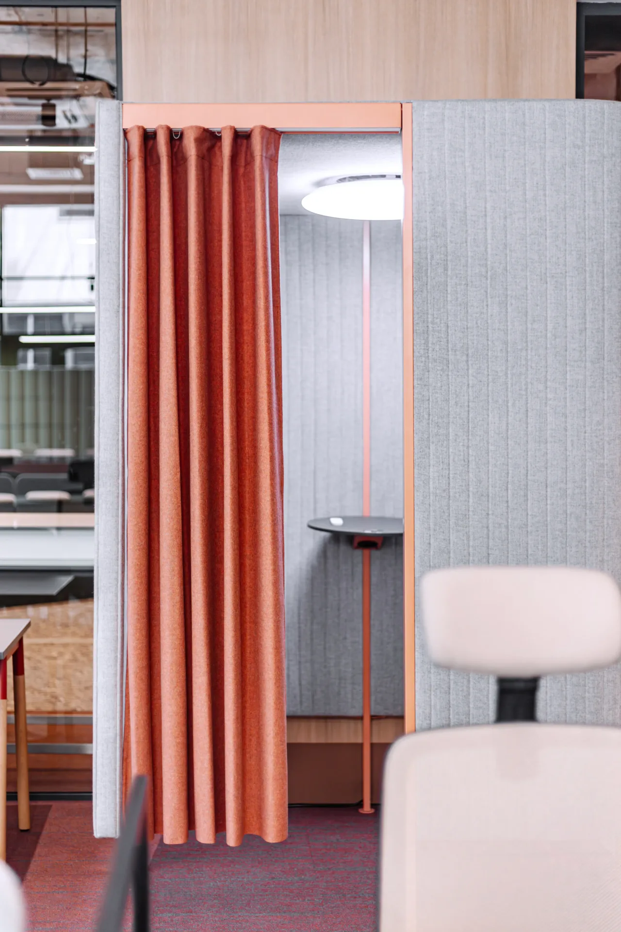 An orange curtain drawn across a booth, a white chair in front