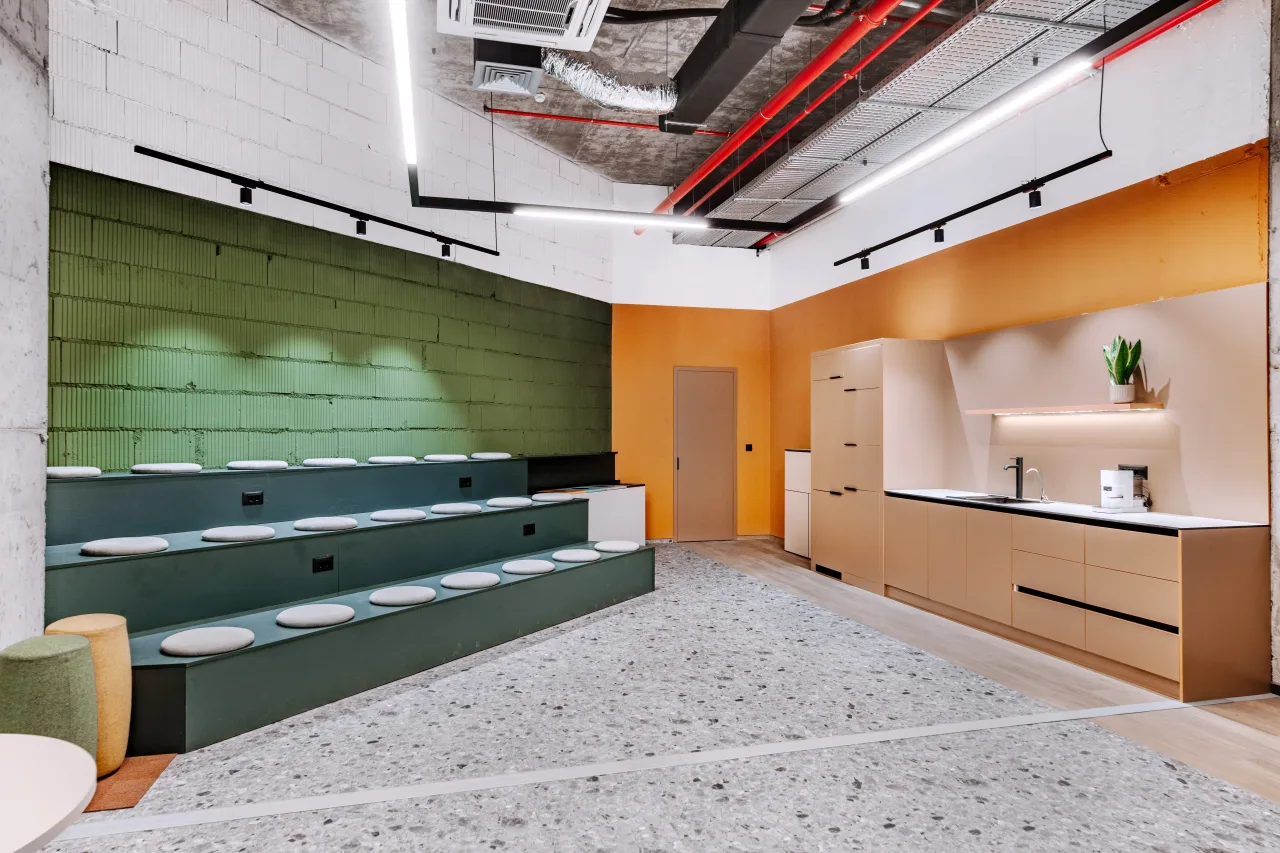 Stepped green seating and an orange kitchen on the open co-working floor