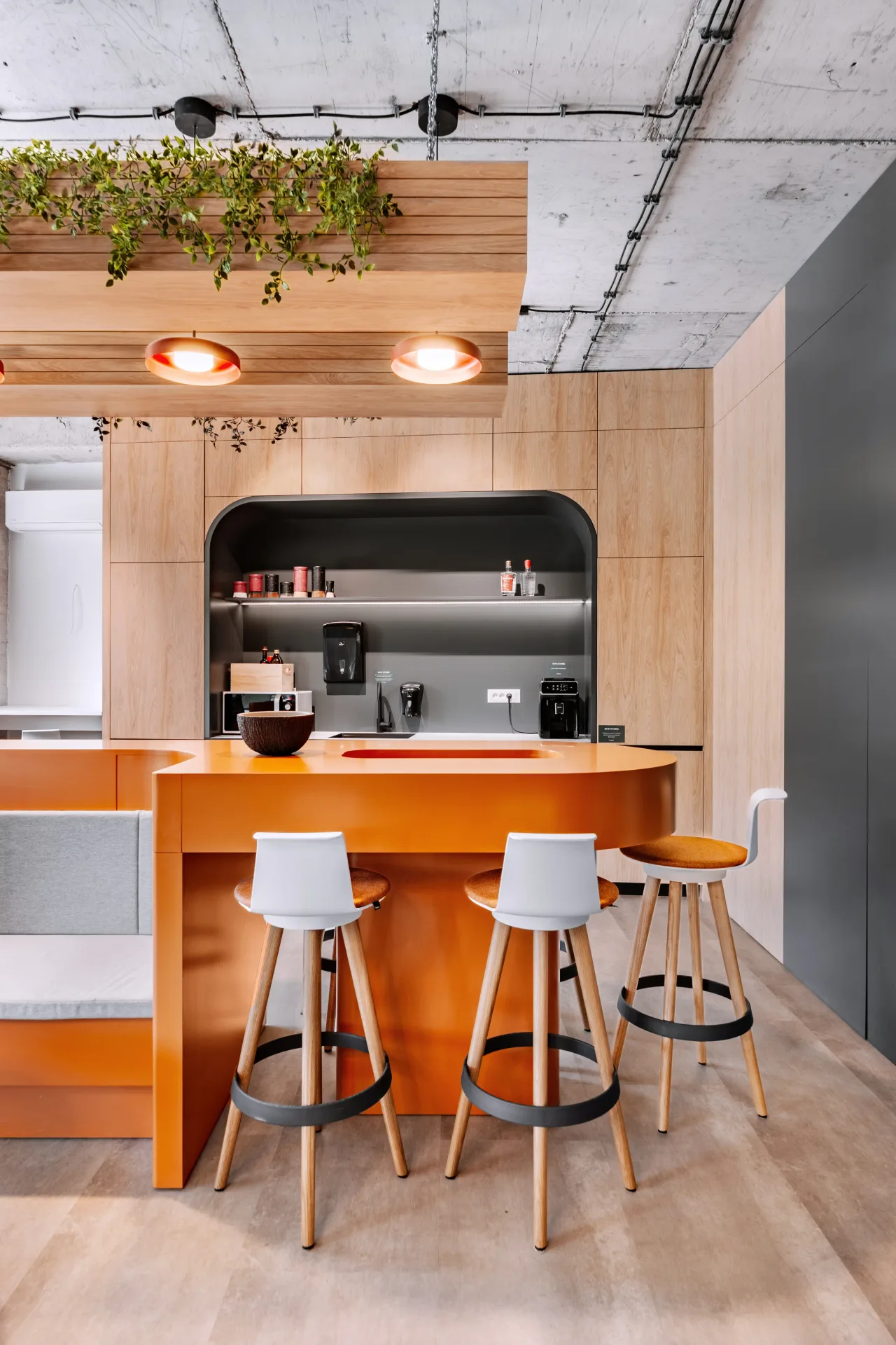 The orange kitchen bar with white stools and planting overhead