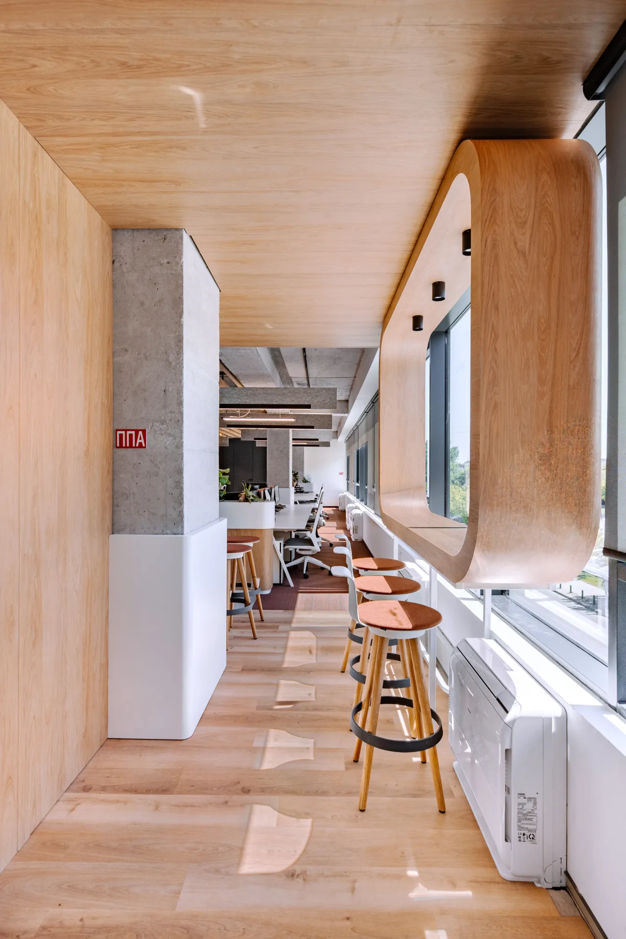 A timber-lined corridor with stools along the window ledge