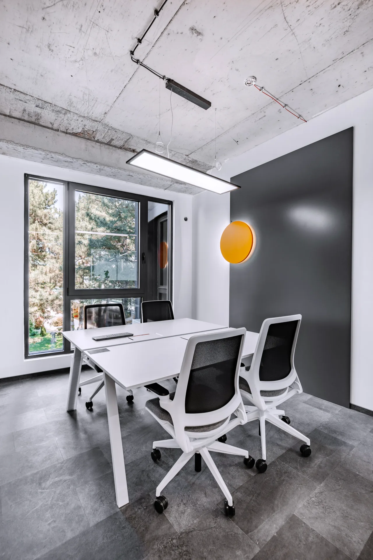 A small meeting room with a white table and an orange lamp