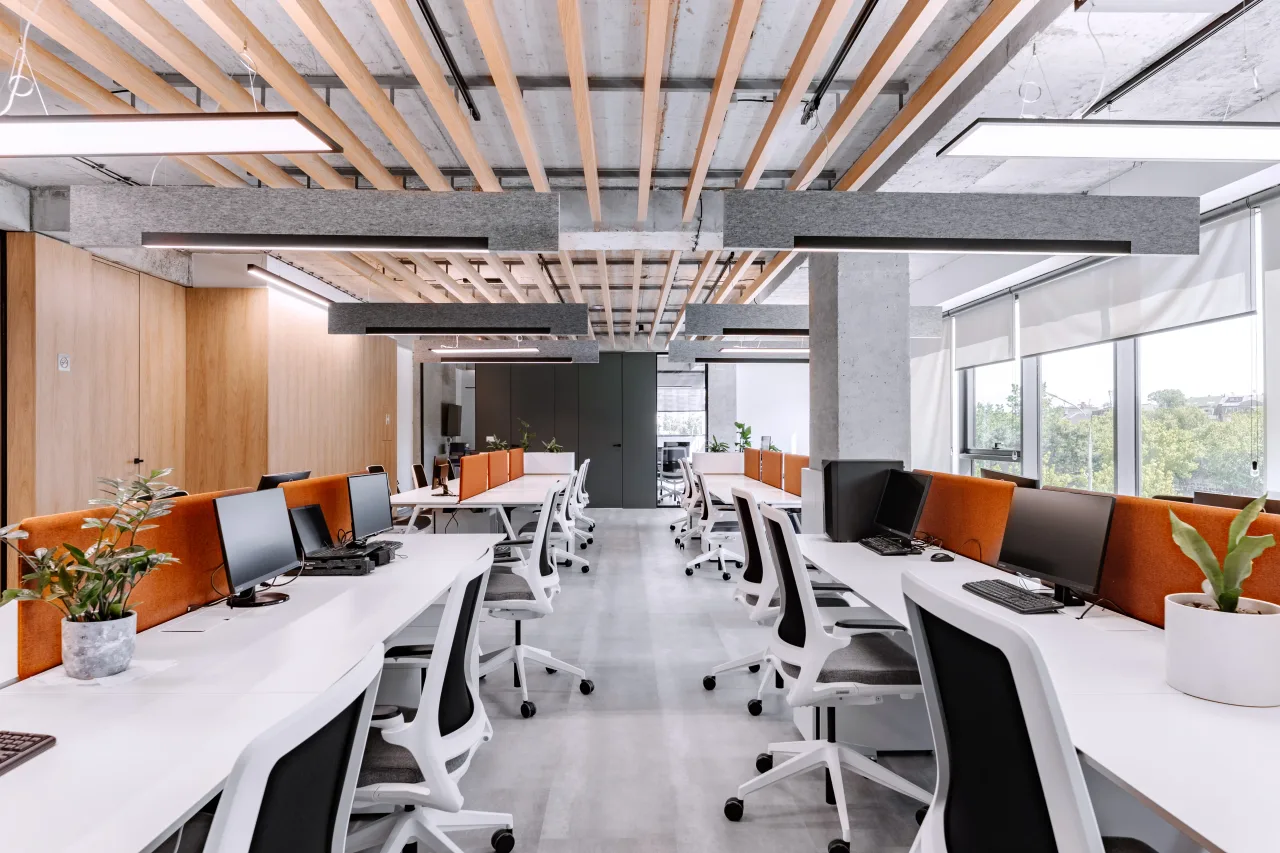 Rows of white desks with orange screens under timber slats