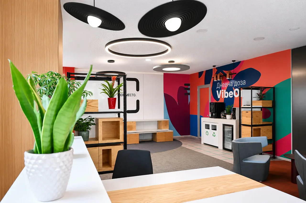 A plant on a white desk, the lounge and mural beyond