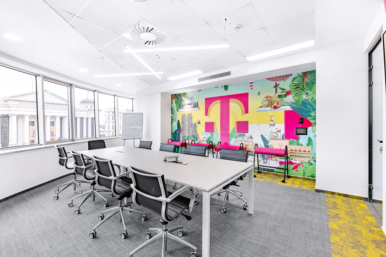 A boardroom with a long table and a mural of the T logo