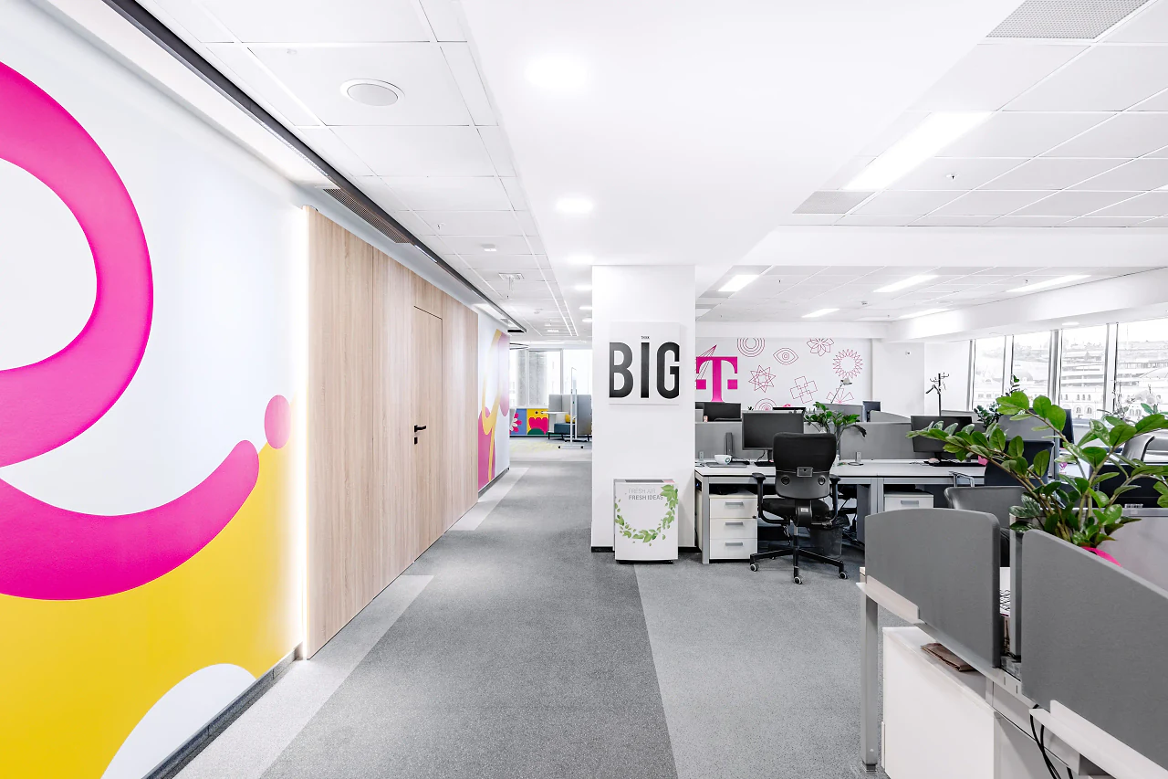 Open desks beside a pink and yellow graphic wall and the BIG T sign