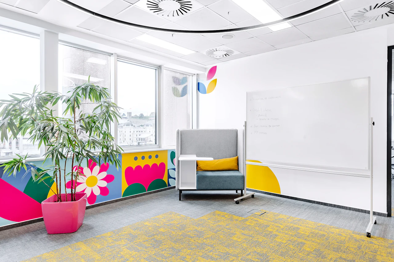 A corner with a flower graphic, a high-backed chair and a whiteboard