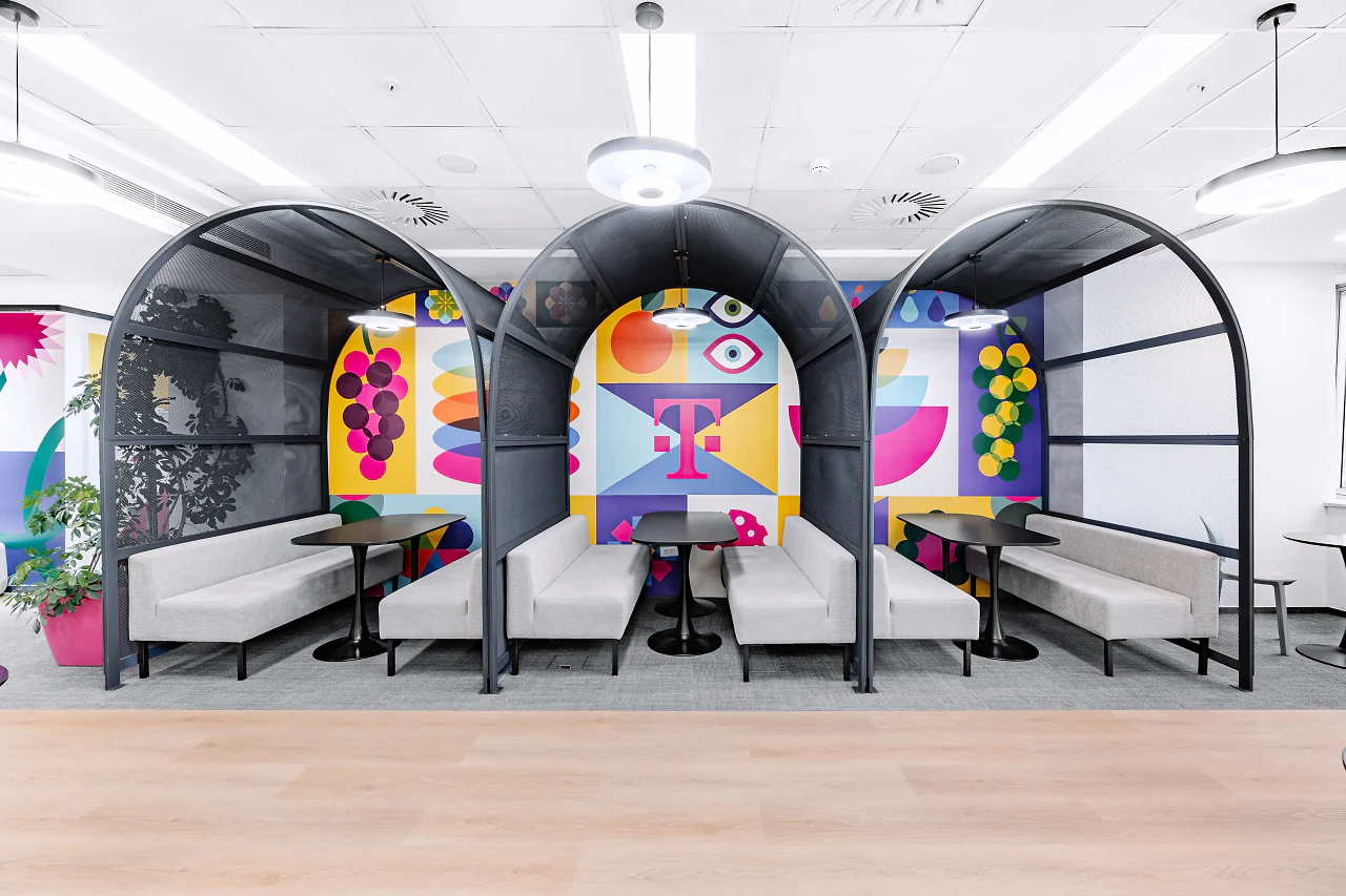 A row of arched black booths with colourful graphic backs and white benches