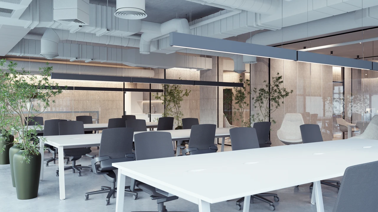 An open office floor with long white desks and exposed services