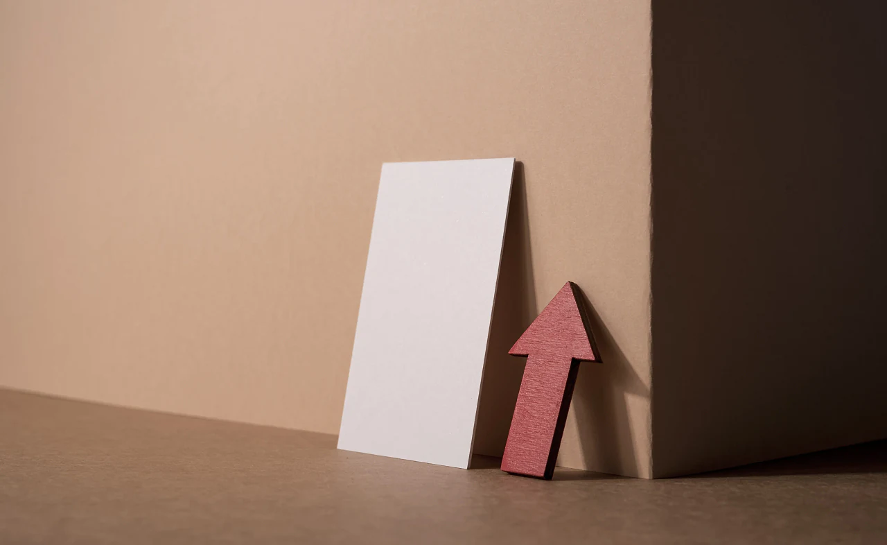 A blank card and a red arrow leaning against a warm beige wall
